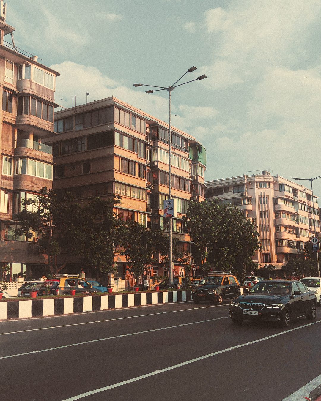 Low-rise residential buildings along a tree-lined Khar road