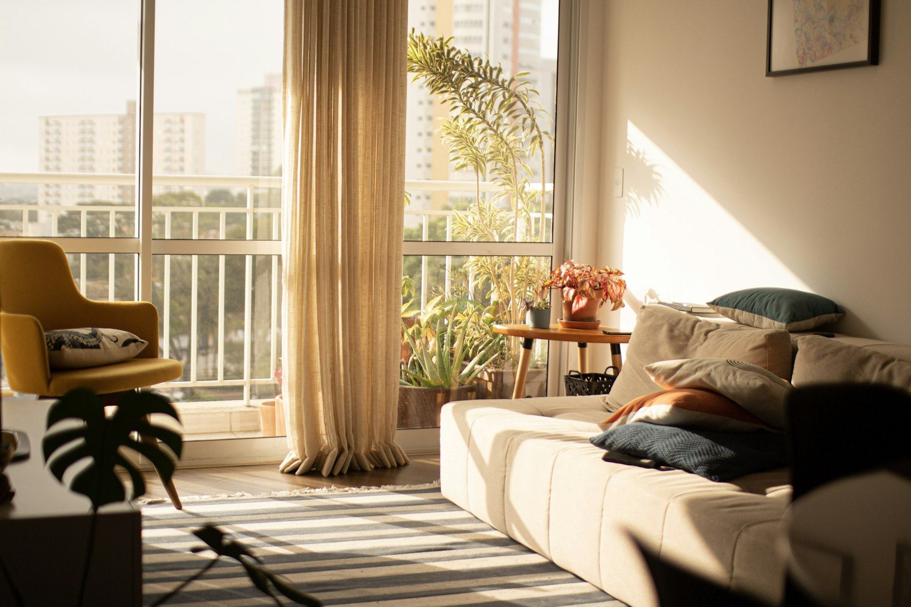 Sunlit living room with a balcony looking out over Mumbai towers